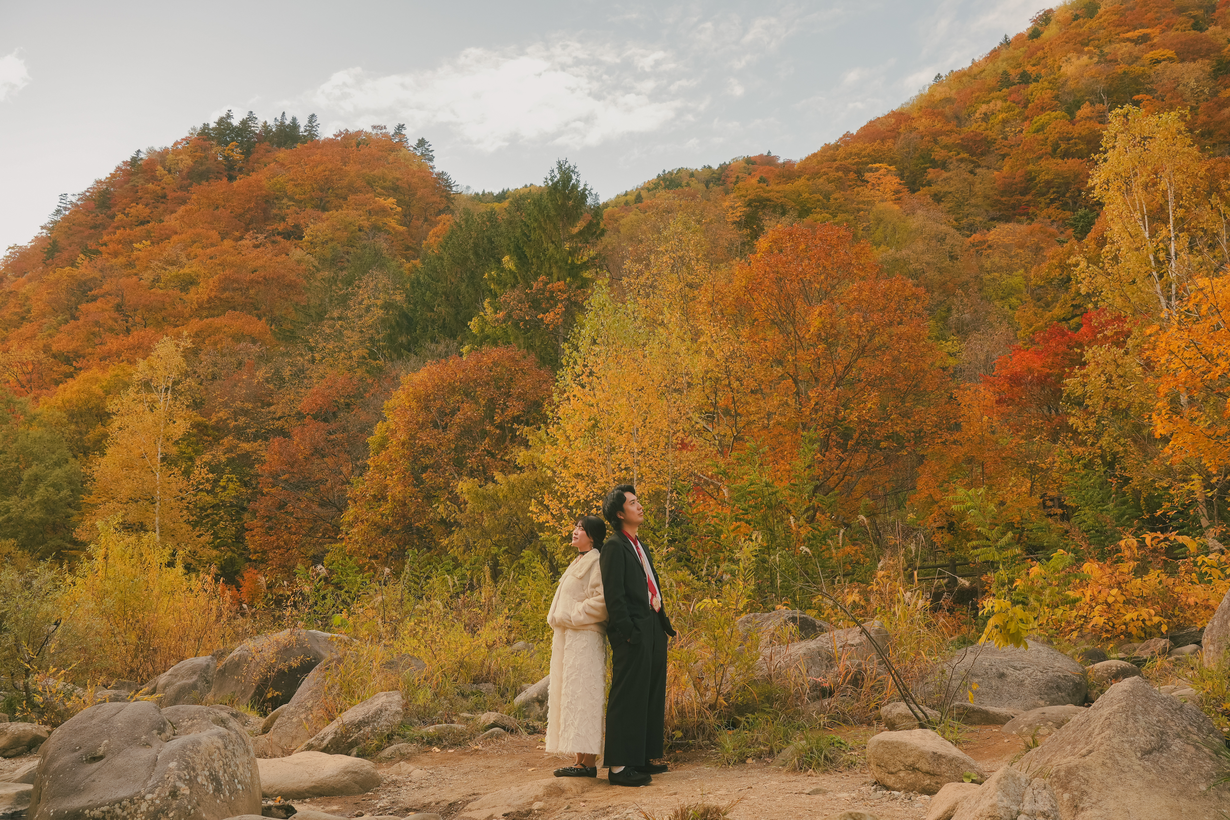 紅葉の山々をバックに背中合わせの男女