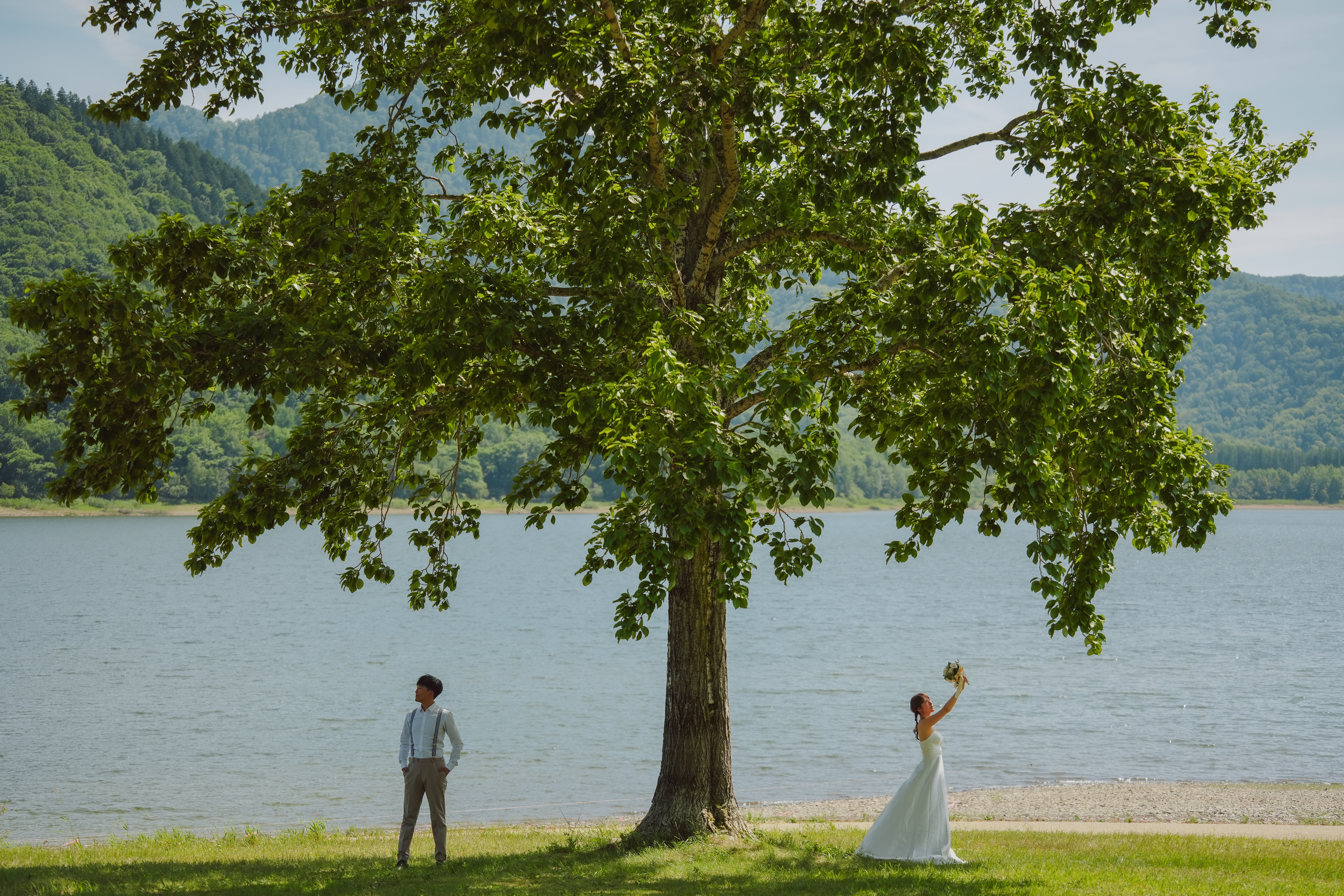 湖近くの木の下でポーズをとる男女