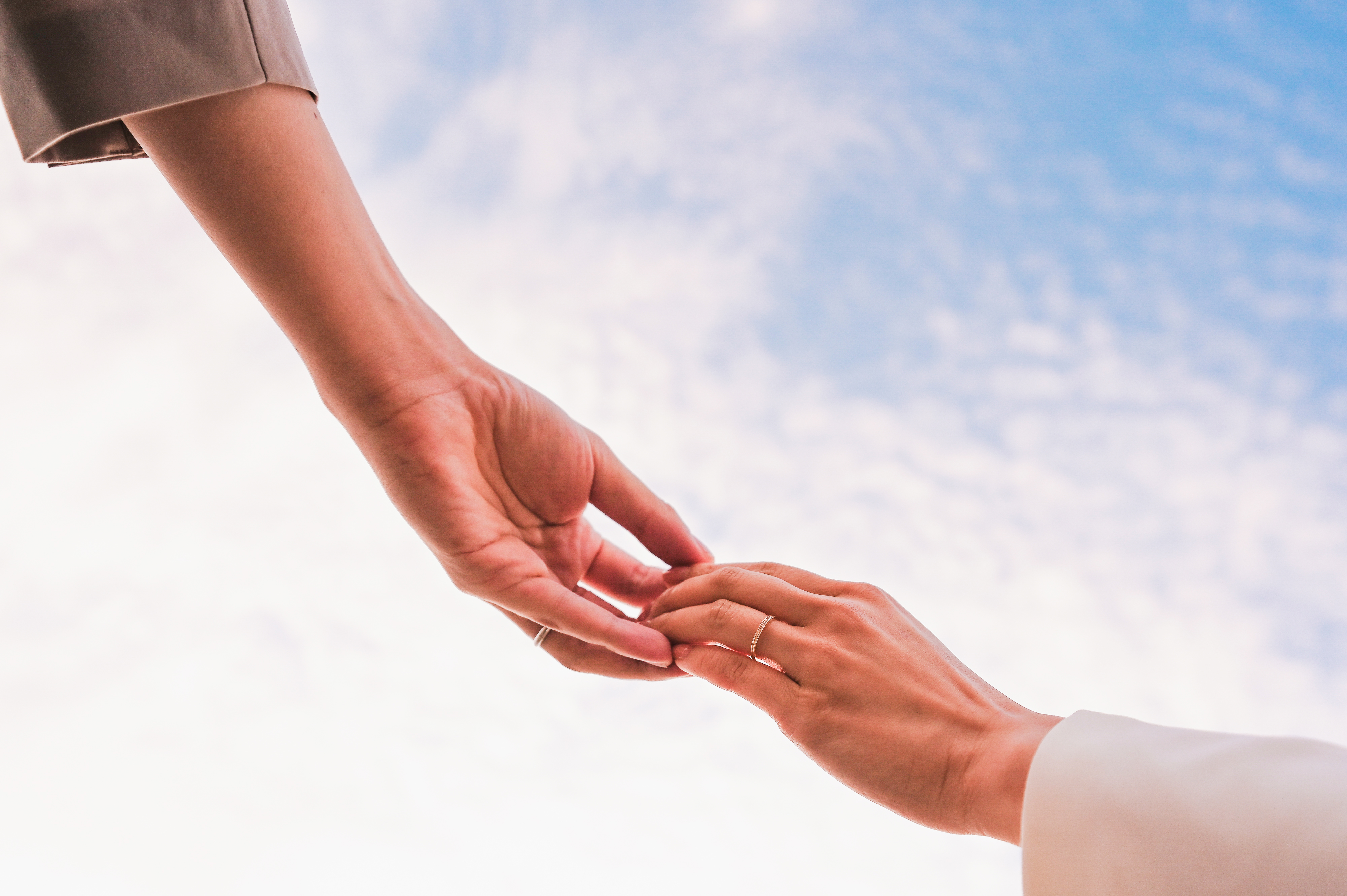 青空を背景に手を取り合うフォト