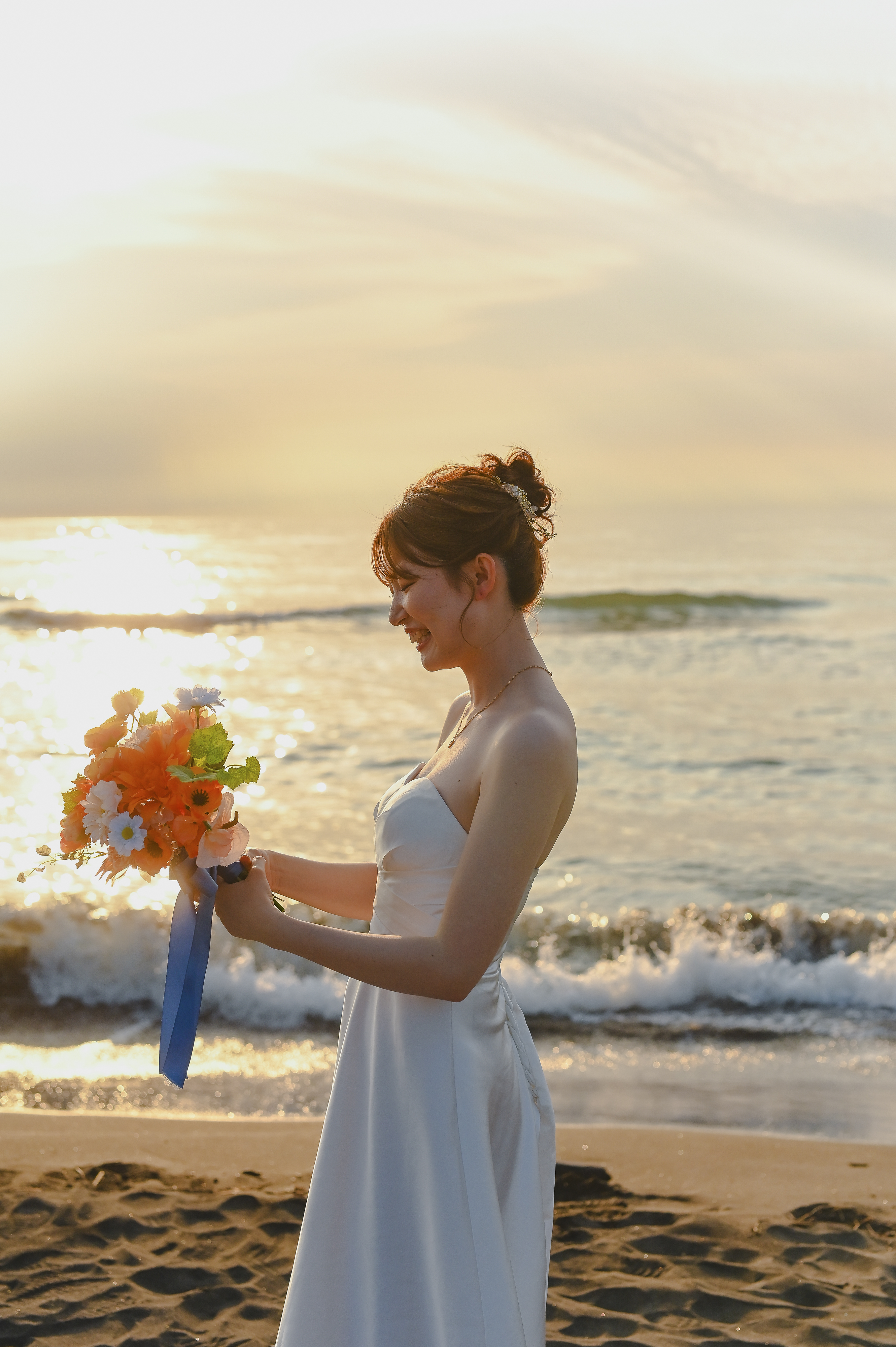 砂浜でブーケを見て微笑む女性